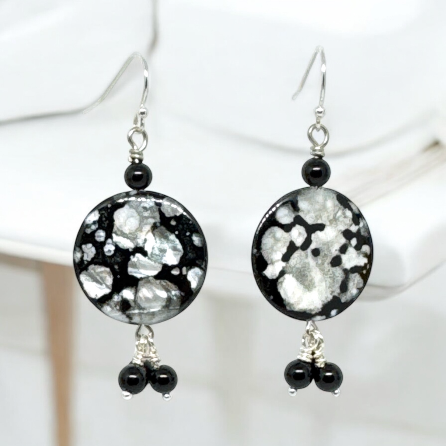 Close-up view of black and metallic disc earrings featuring textured discs and smooth dark beads, showcasing their modern and chic design.