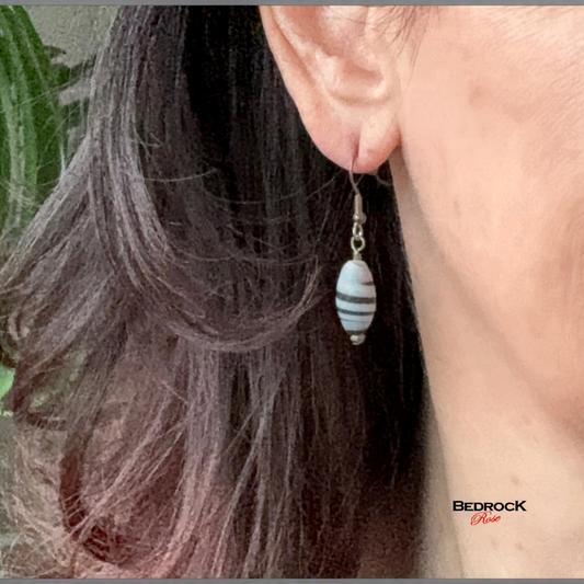 Bedrock Rose black and white swirl glass bead drop earrings worn on an earlobe