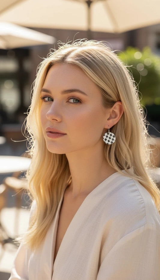 Blonde woman wearing Bedrock Rose handmade kiln-fired copper disc earrings with a black and white checkerboard pattern.