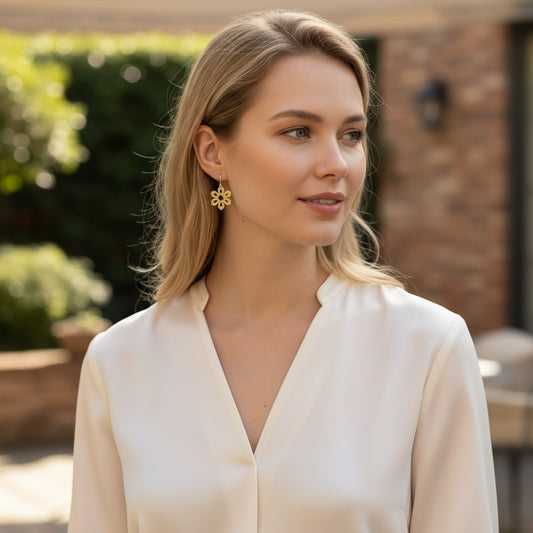 Bedrock Rose gold-plated brass Art Deco flower earrings worn by a woman in a white blouse.
