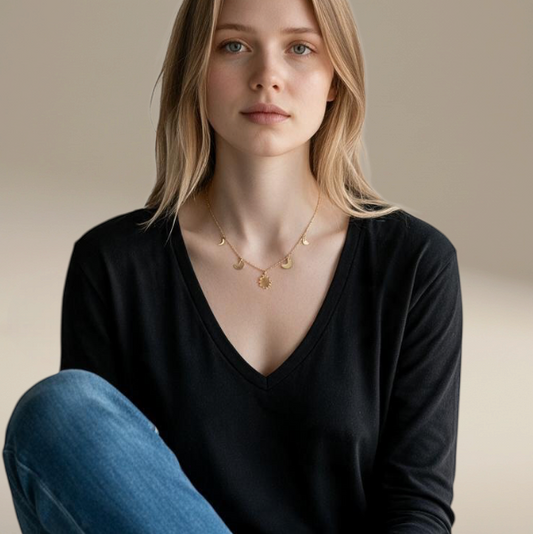 Bedrock Rose gold-fill necklace featuring moon phase charms on a dainty chain worn by a woman in a black v-neck top.