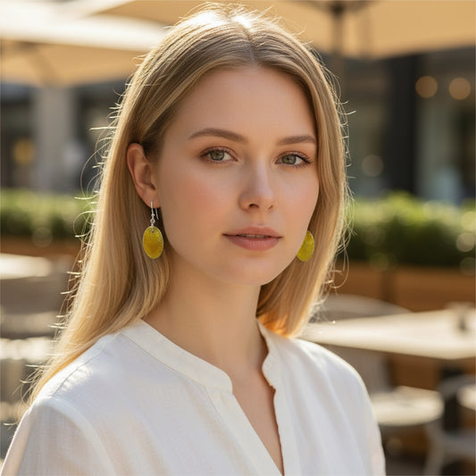 Bedrock Rose oval honeycomb earrings in amber-gold enamel on fine silver worn by a woman in a white blouse.
