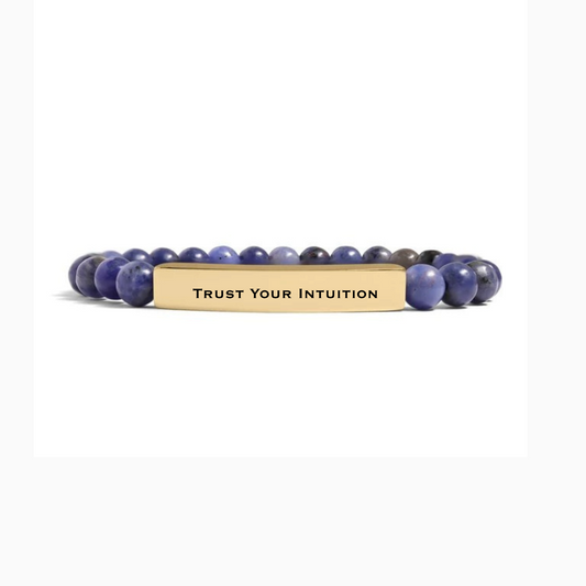 Bedrock Rose stretch bracelet with blue sodalite beads and a gold curved bar engraved with Trust Your Intuition.
