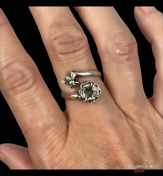 Bedrock Rose sterling silver wrap ring featuring a detailed honeybee and blossom with an oxidized patina on a finger.