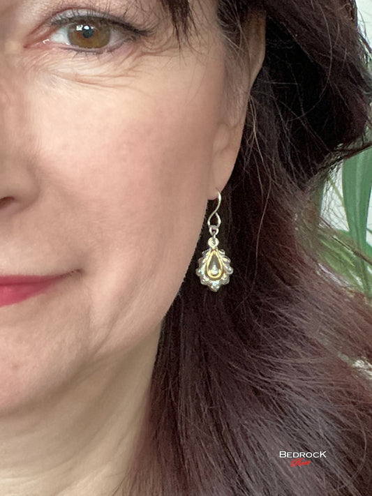 Bedrock Rose die-struck sterling silver teardrop earrings with 24k gold accents worn on a woman's ear