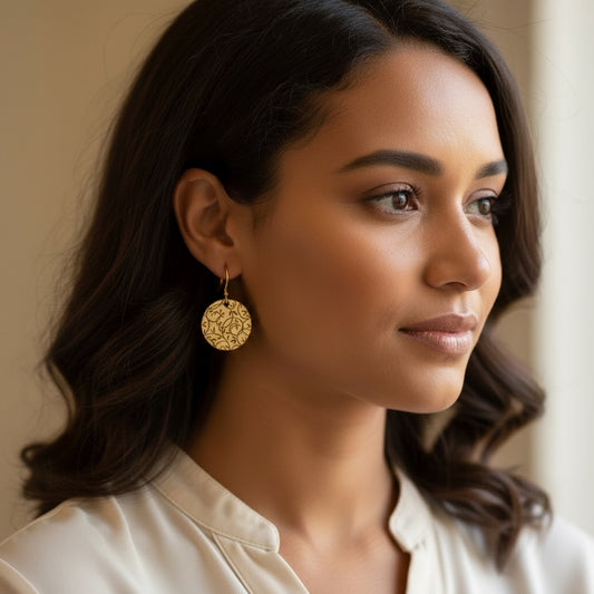 Bedrock Rose gold-tone disc earrings with all-over botanical vine lattice etching. Dangles hang from gold hooks.