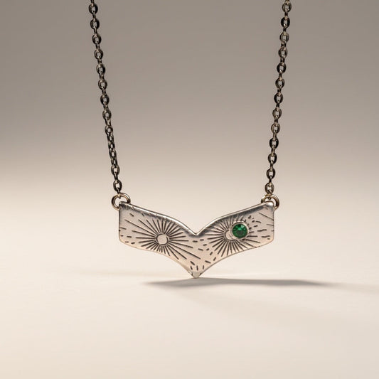 Bedrock Rose silver chevron pendant necklace with radiating line pattern and emerald-nanogem accent.
