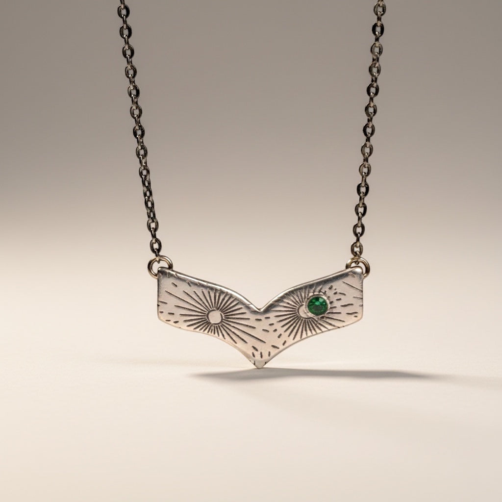 Bedrock Rose silver chevron pendant necklace with radiating line pattern and emerald-nanogem accent.