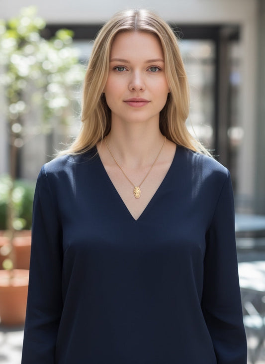 Bedrock Rose wildflower pendant in rose bronze, featuring delicate floral engraving on a hexagonal shape, worn on an 18" brass chain.