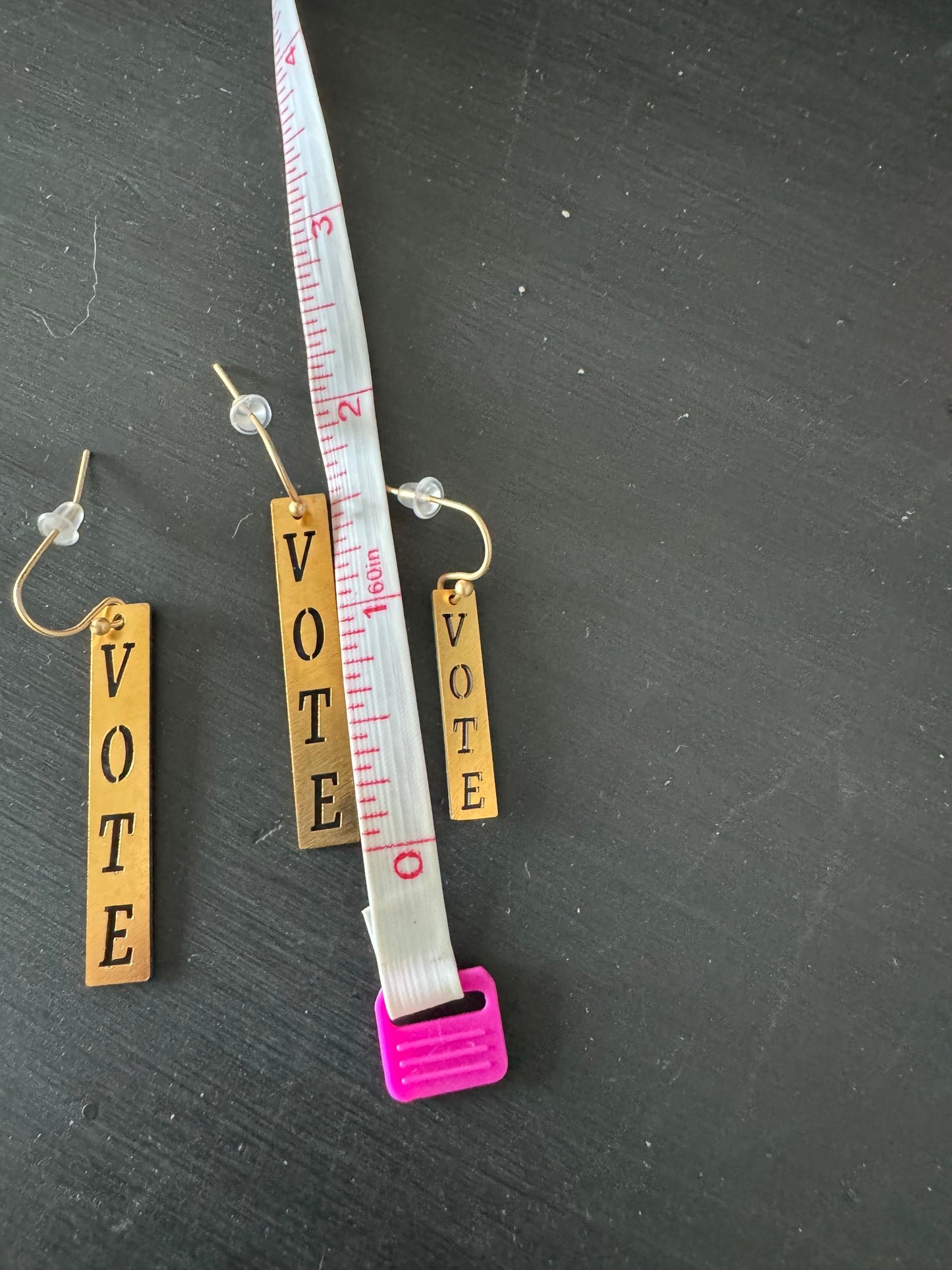 Vote earrings two sizes next to ruler