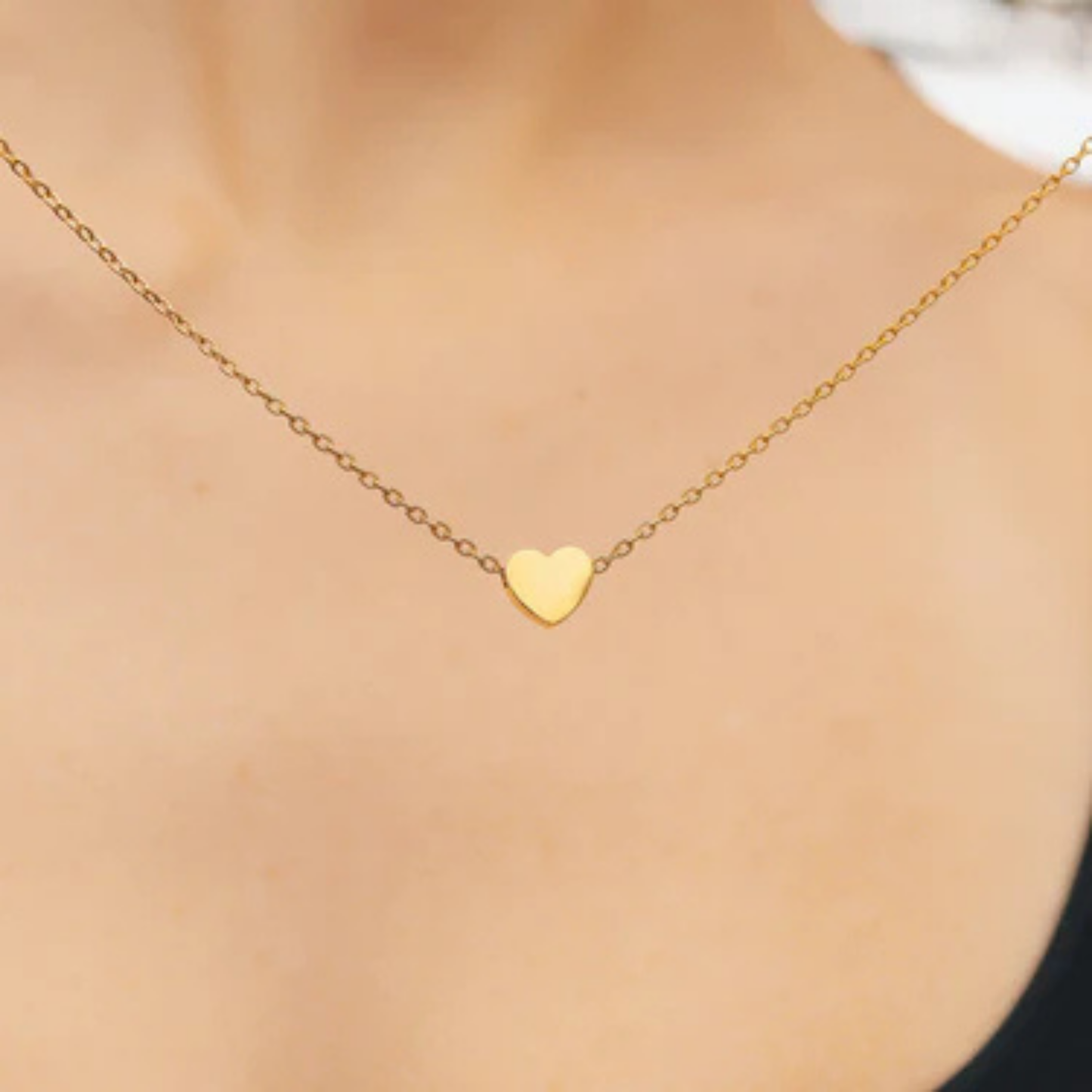 Gold heart-shaped necklace on a person's neck