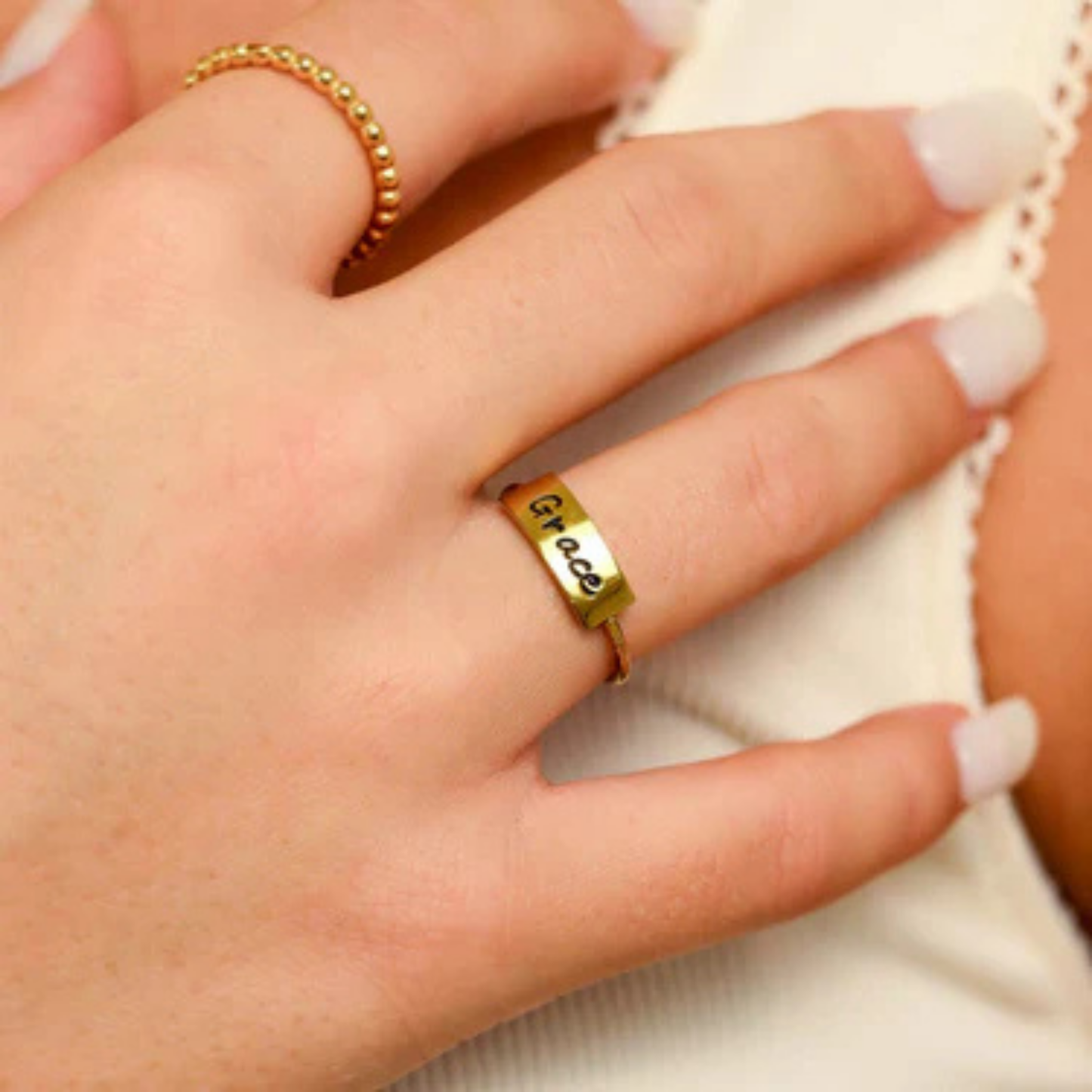 Gold ring with 'Grace' engraved on a person's finger