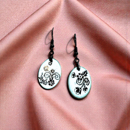 Pair of earrings with floral design on a pink fabric background
