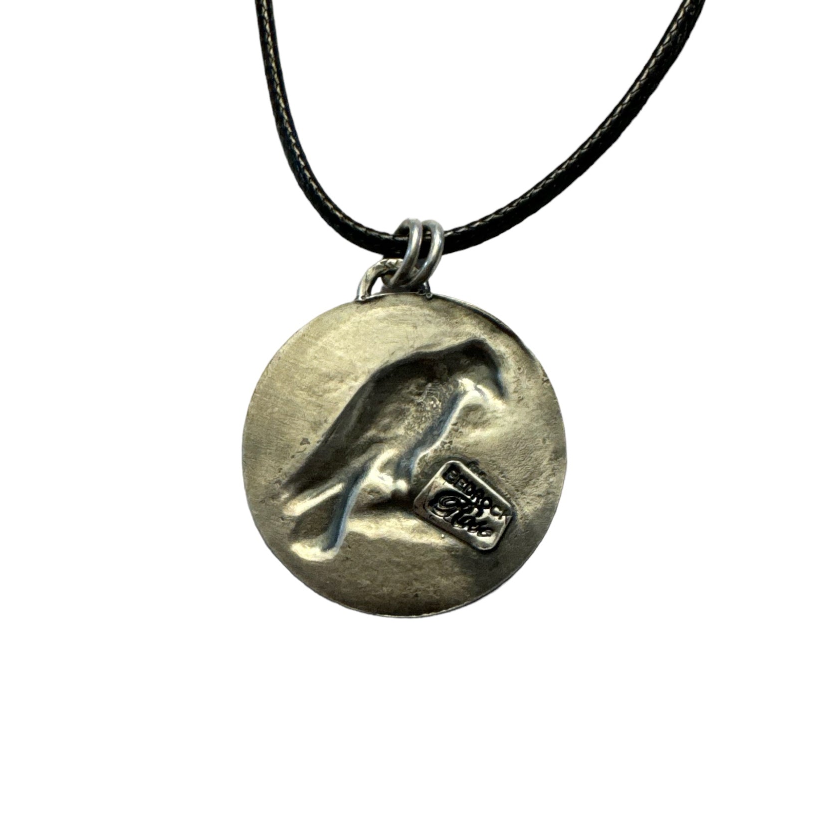 Back view of detailed crow design on the round silver pendant