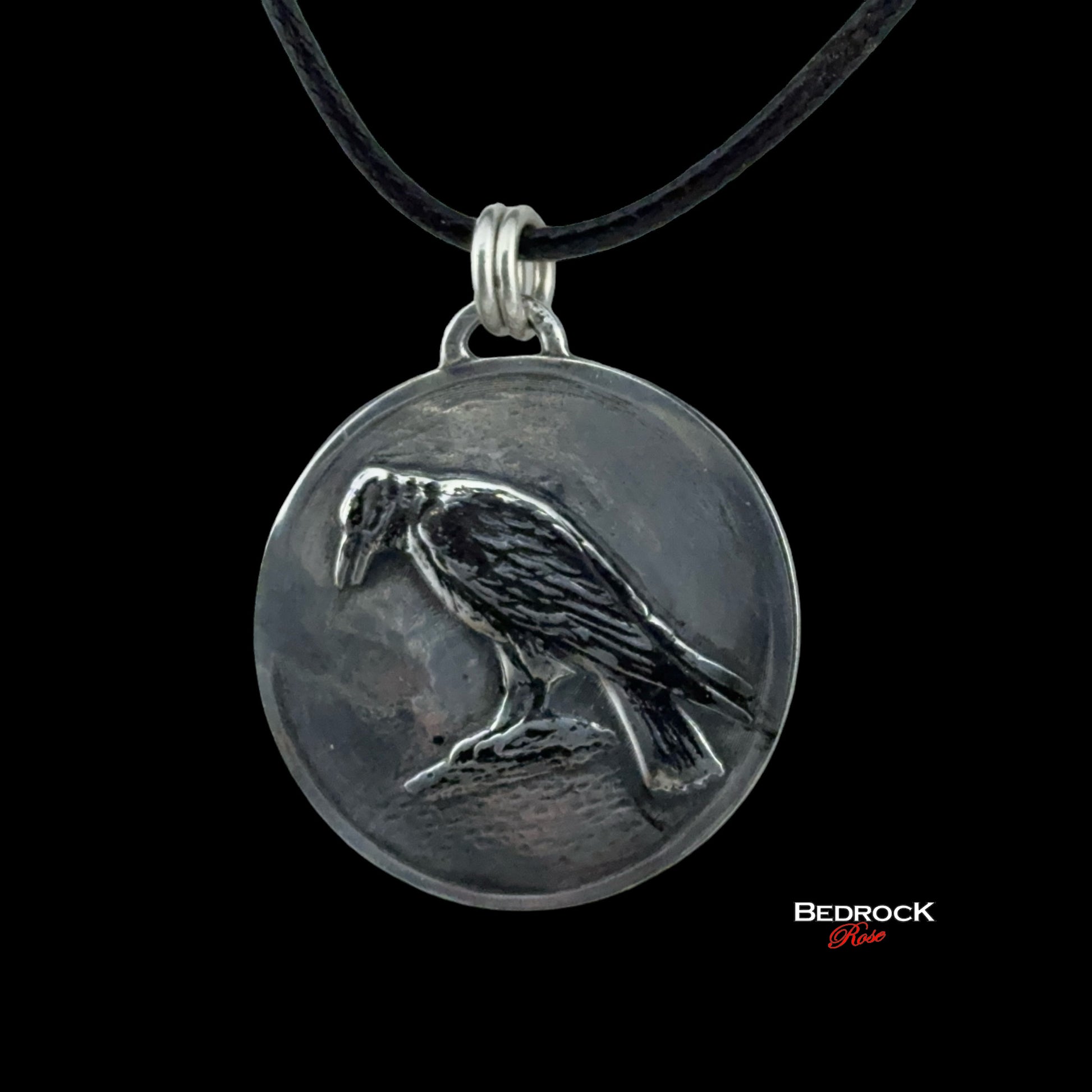 Close-up view of detailed crow design on the round silver pendant