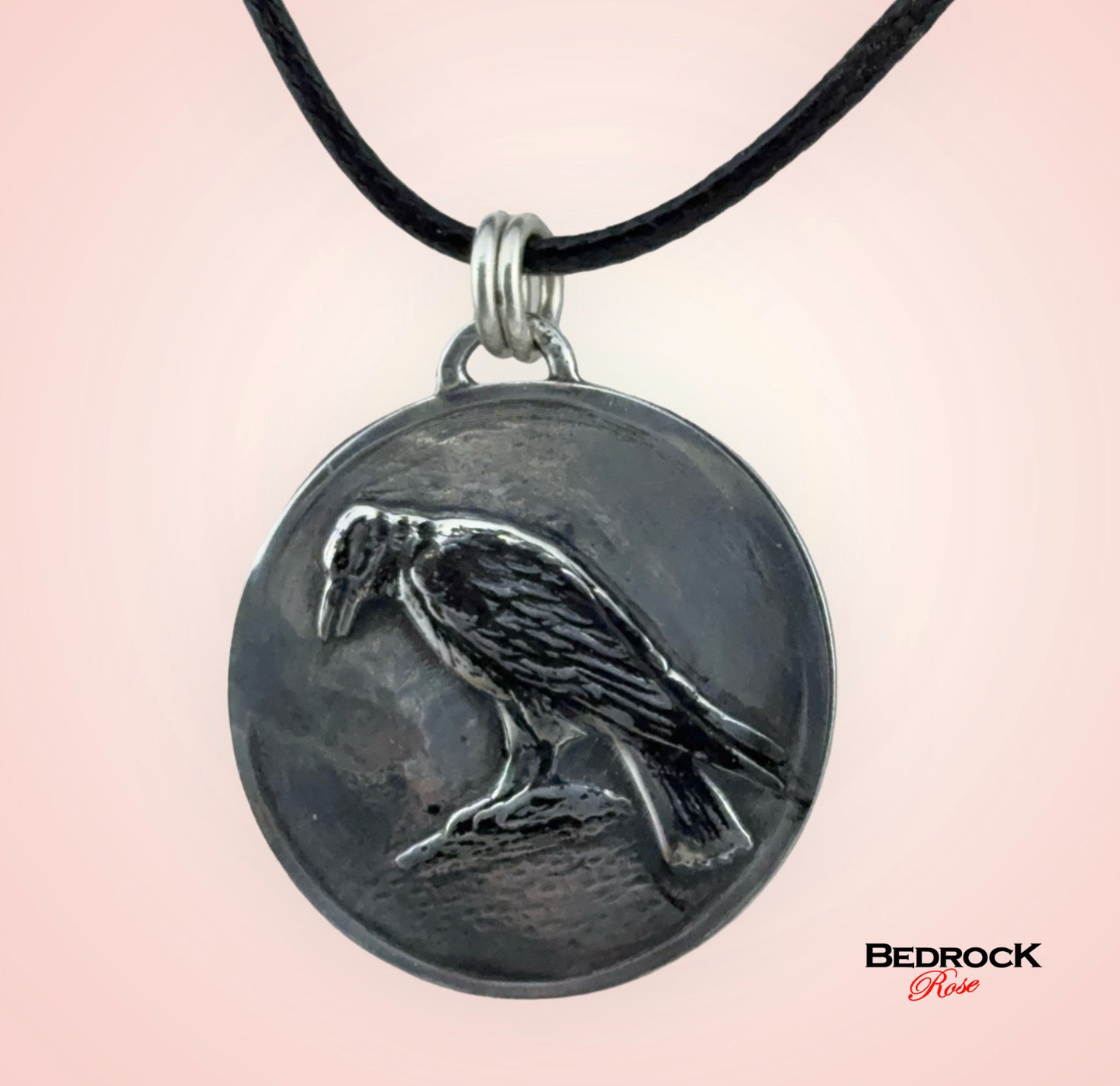 Close-up view of detailed crow design on the round silver pendant