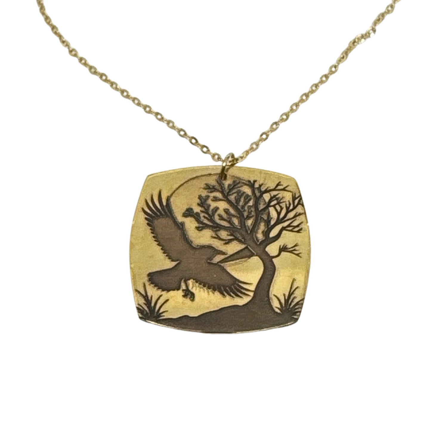 Detailed view of the laser-engraved crow and tree design on the gold-plated brass pendant, highlighting the intricate details.