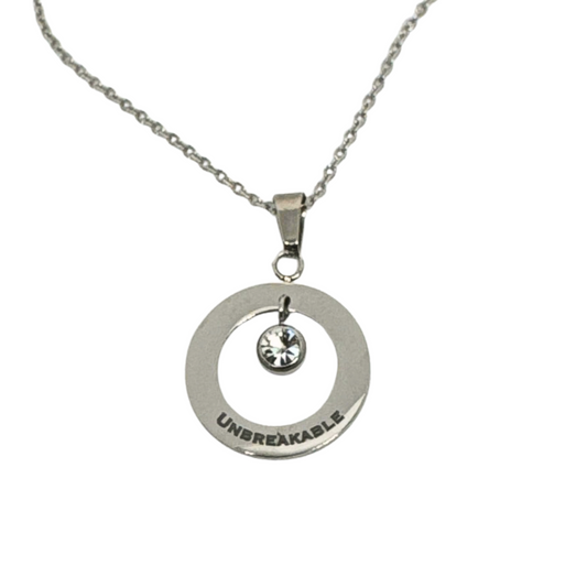 Close-up of a silver stainless steel circle pendant necklace with a crystal accent and the word 'Unbreakable' engraved on it.