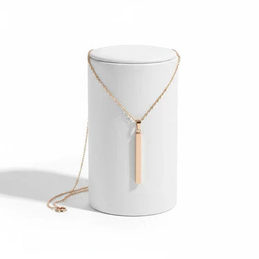 Gold necklace on a white cylindrical stand against a white background