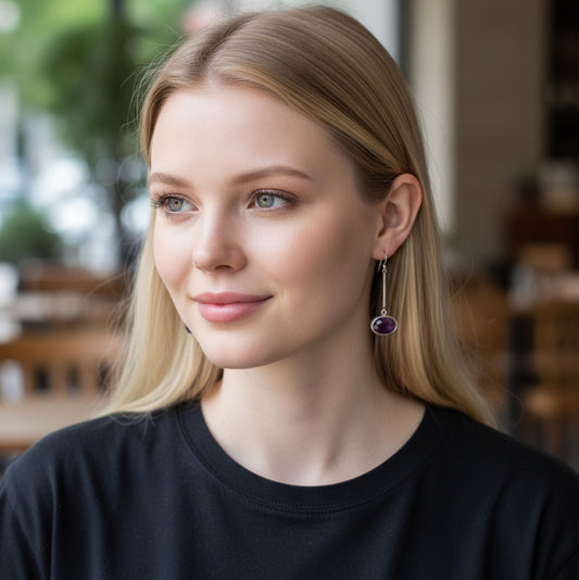 Bedrock Rose oval amethyst drop earrings in sterling silver worn by a blonde woman in a black shirt