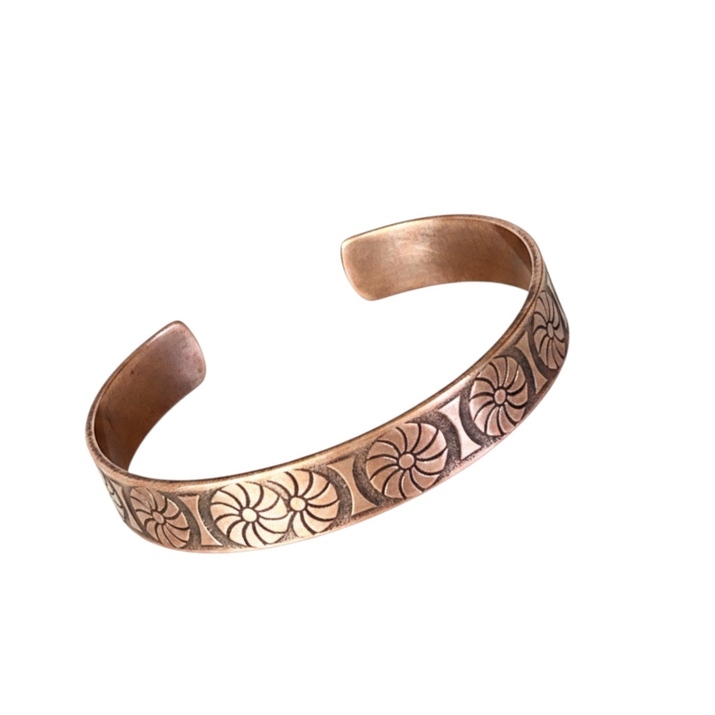 Bedrock Rose antique copper cuff bracelet with a repeating floral sunburst pattern and a dark hand-patinated finish.