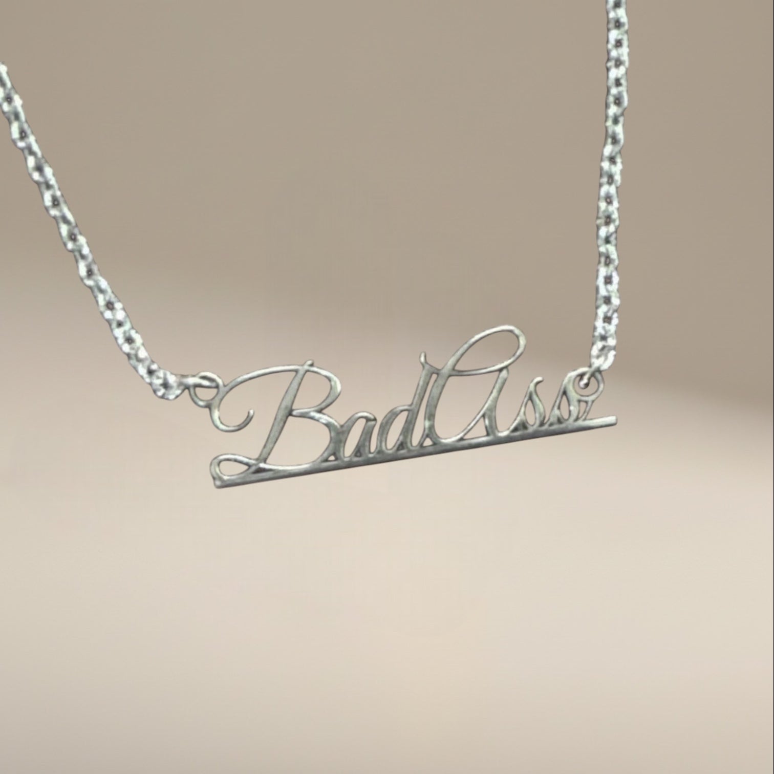Bedrock Rose sterling silver Bad Ass script pendant necklace on a sleek stainless steel chain.