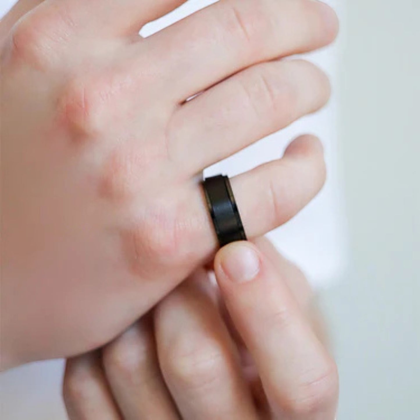 Bedrock Rose black stainless steel spinner ring worn on a finger, featuring a sleek matte finish for anxiety relief.