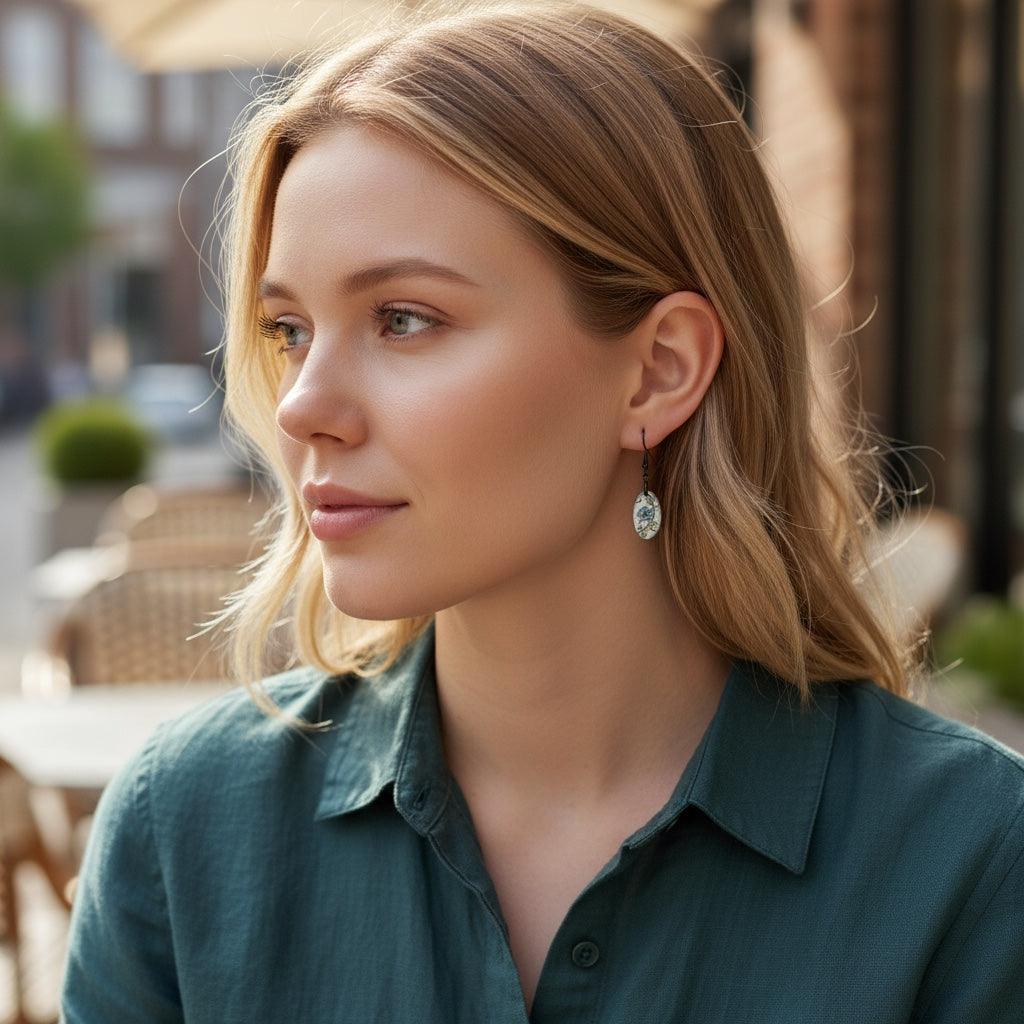 Bedrock Rose hand-painted oval dangle earrings with blue flowers and green leaves on white enamel.