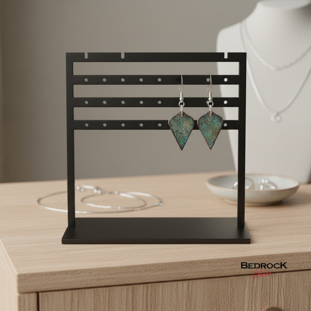 Bedrock Rose copper enamel shield earrings with mossy green and charcoal patina on a black display stand