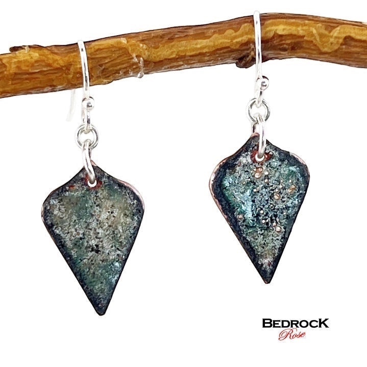Bedrock Rose copper enamel shield earrings with mossy green and charcoal forest floor patina on surgical steel wires.