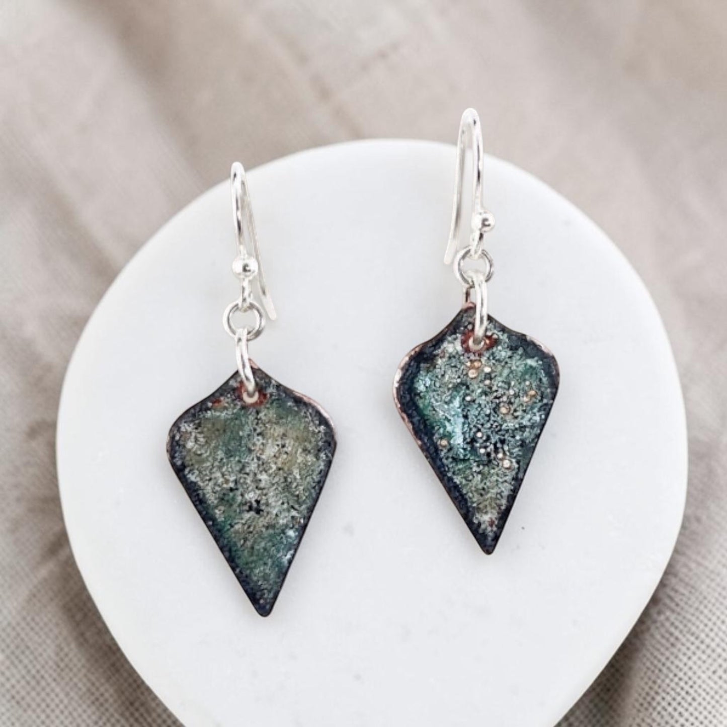 Bedrock Rose handcrafted copper shield earrings with mossy green and charcoal enamel and shimmering mica accents.
