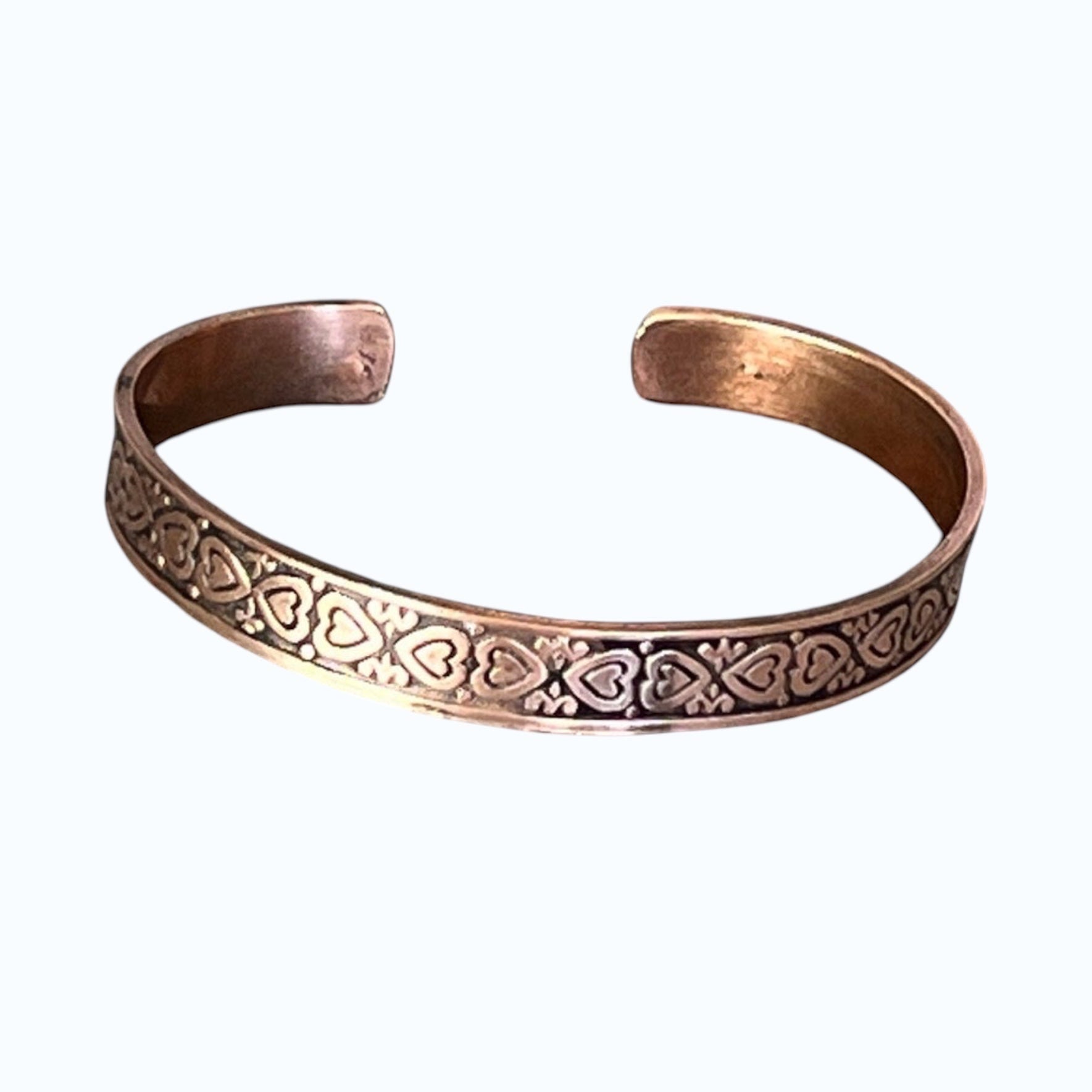Bedrock Rose copper cuff bracelet featuring a repeating heart and filigree pattern with a dark antique patina finish.