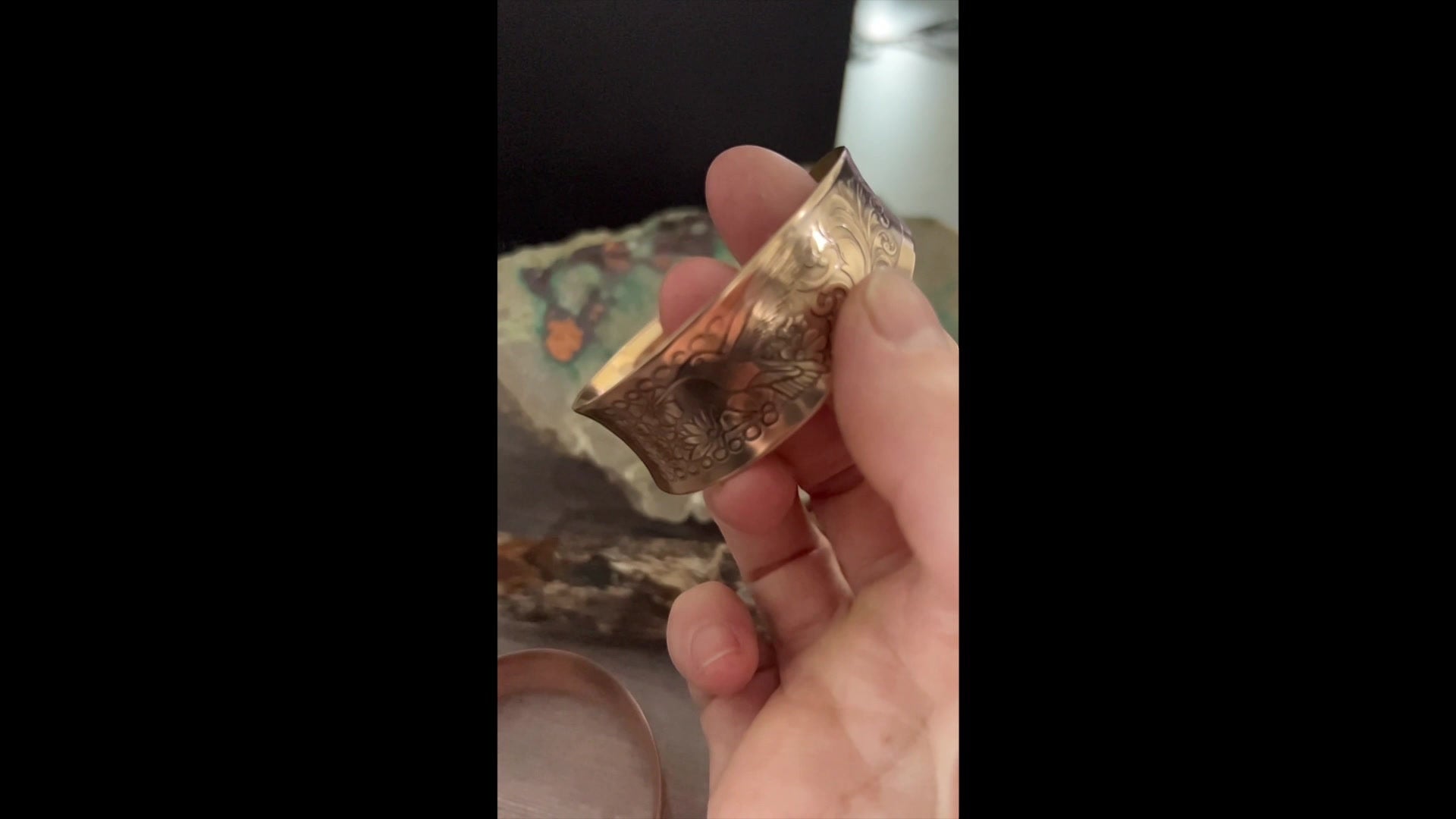 Bedrock Rose polished copper hummingbird cuff bracelet with an elegant concave design held in a hand.