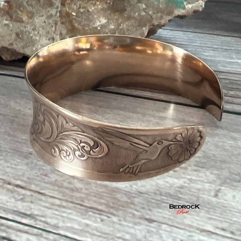 Bedrock Rose polished copper hummingbird cuff bracelet with an elegant concave design and intricate floral engraving.