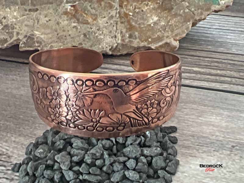 Bedrock Rose copper cuff bracelet featuring an embossed hummingbird and floral design with a polished finish.