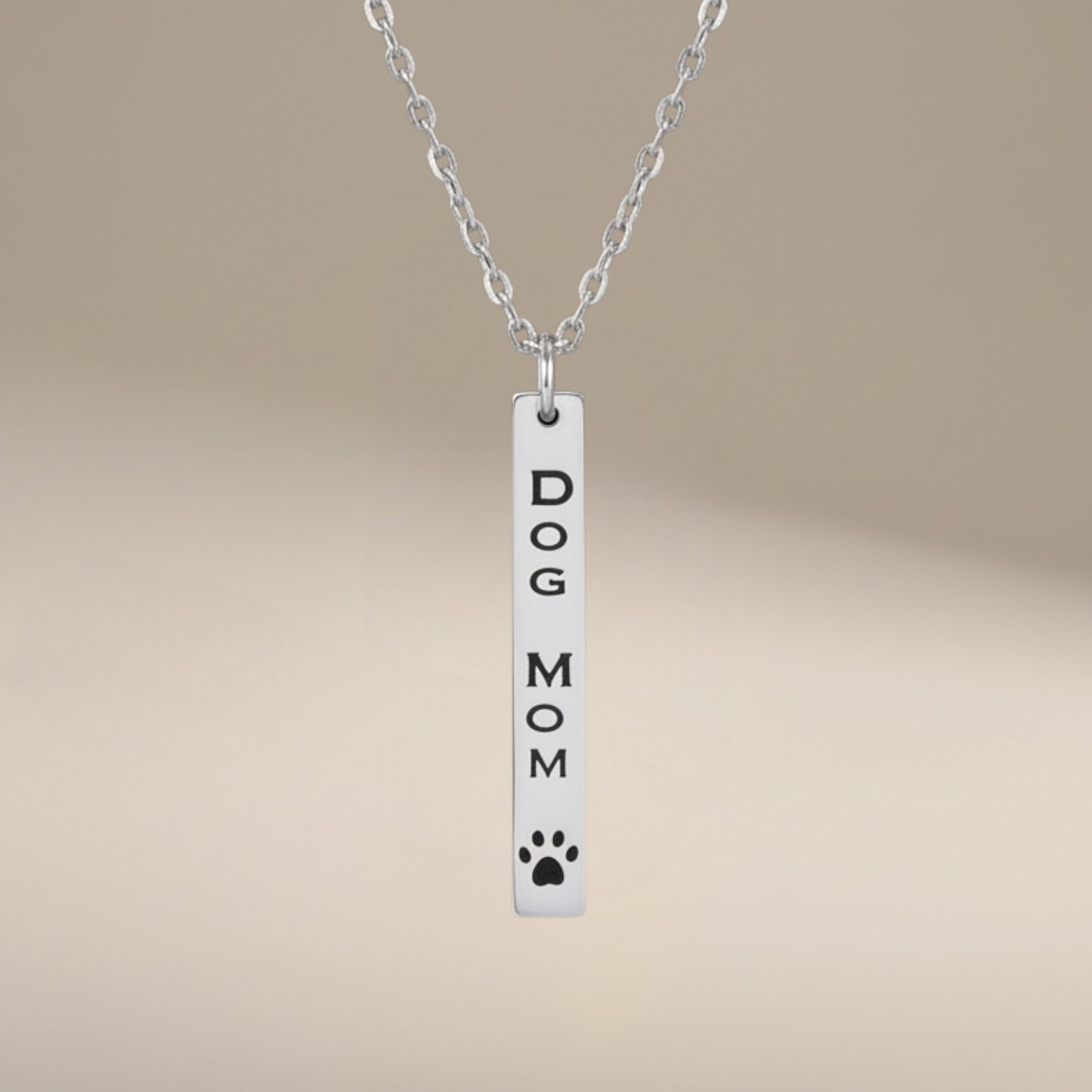 Bedrock Rose Dog Mom necklace with vertical bar pendant, engraved text and paw print detail, made of polished silver stainless steel.