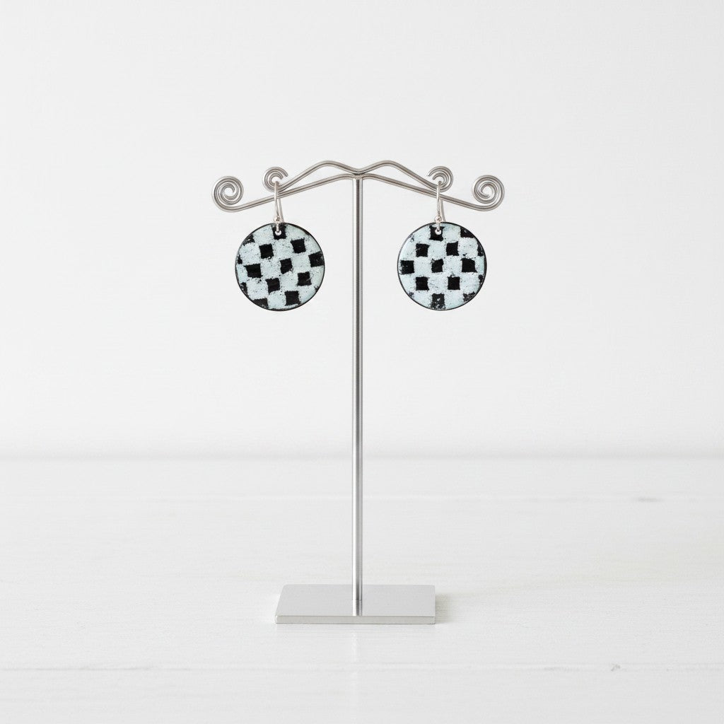 Bedrock Rose handmade round copper dangle earrings with a black and white kiln-fired enamel checkerboard pattern.