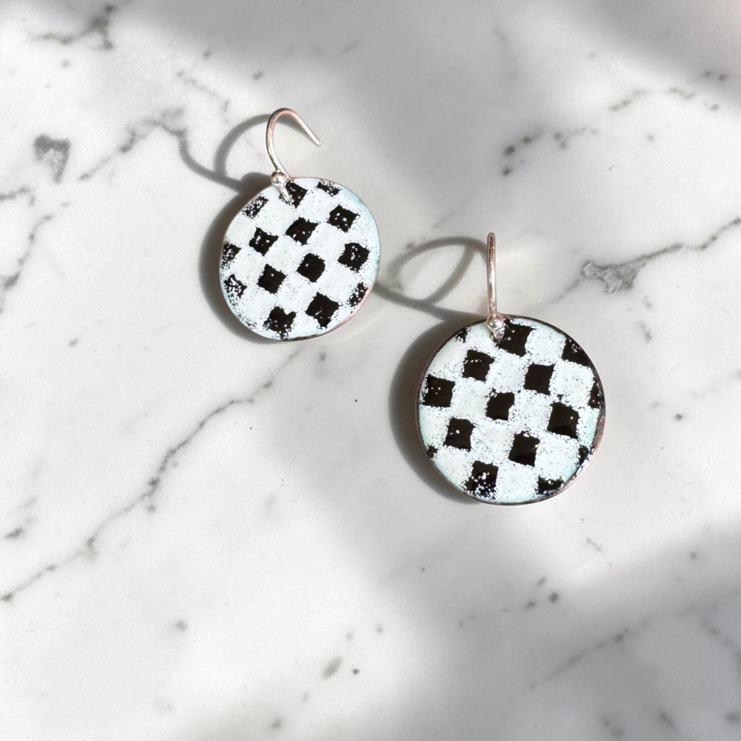 Bedrock Rose handmade copper disc earrings with a black and white kiln-fired enamel checkerboard pattern.