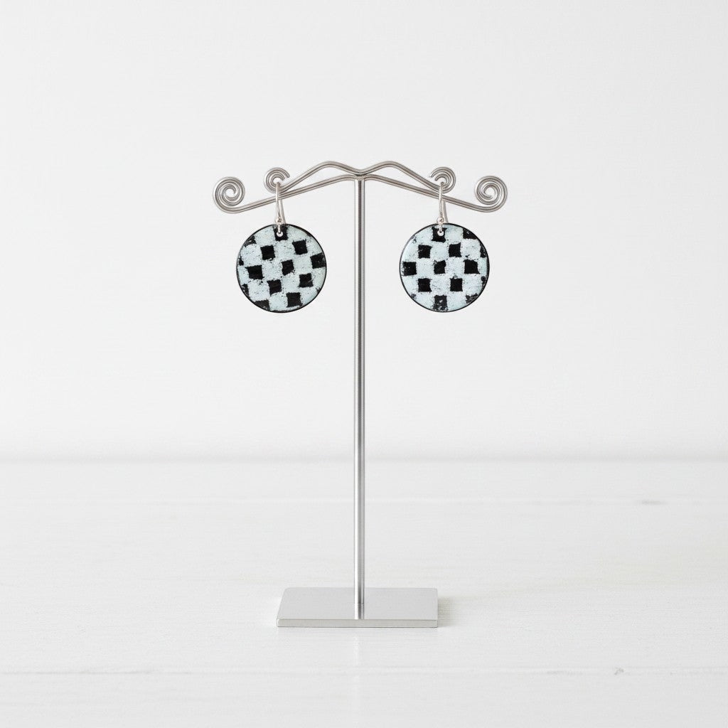 Bedrock Rose handmade round copper dangle earrings with a black and white kiln-fired enamel checkerboard pattern.