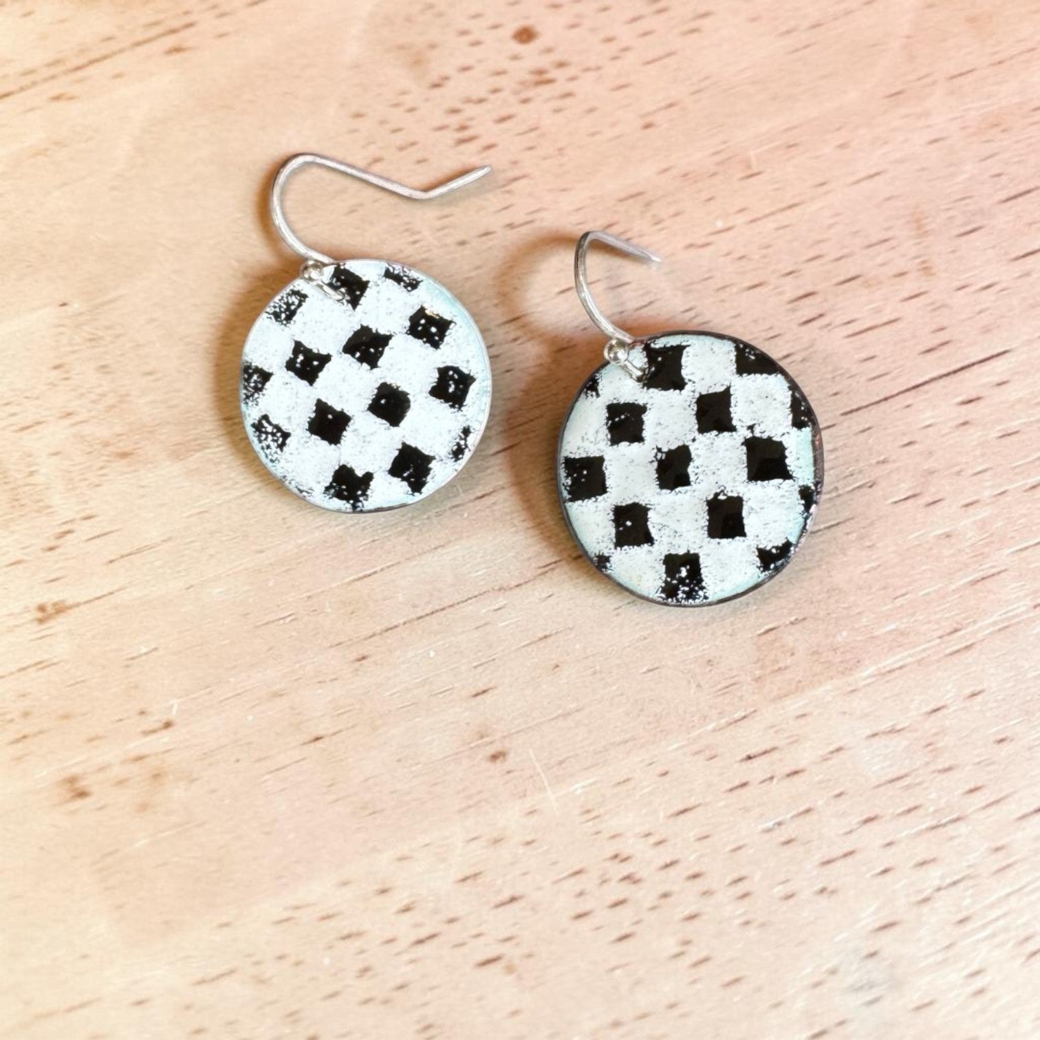 Bedrock Rose handmade round copper dangle earrings with a textured black and white kiln-fired enamel checkerboard.