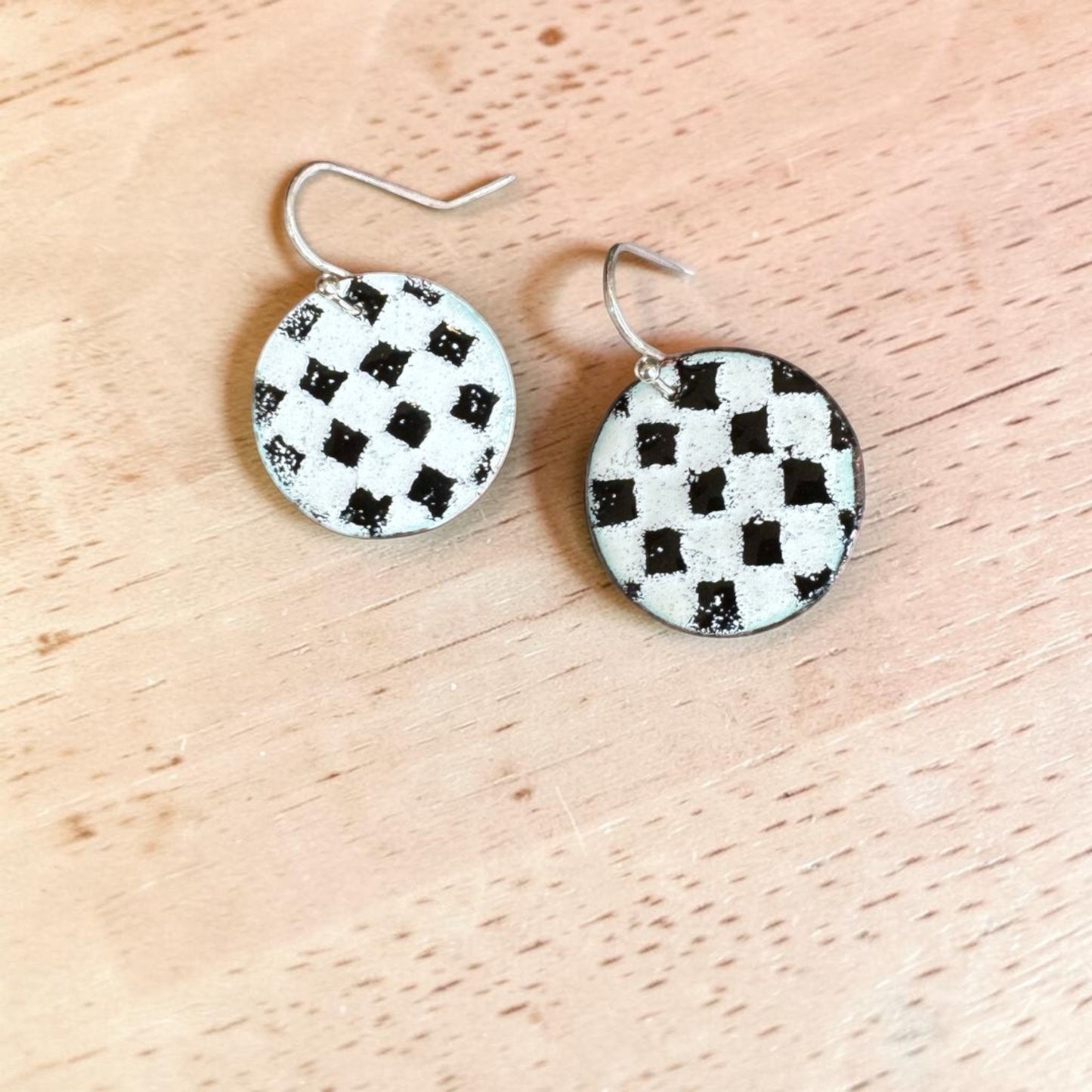 Bedrock Rose handmade round copper dangle earrings with a textured black and white kiln-fired enamel checkerboard.