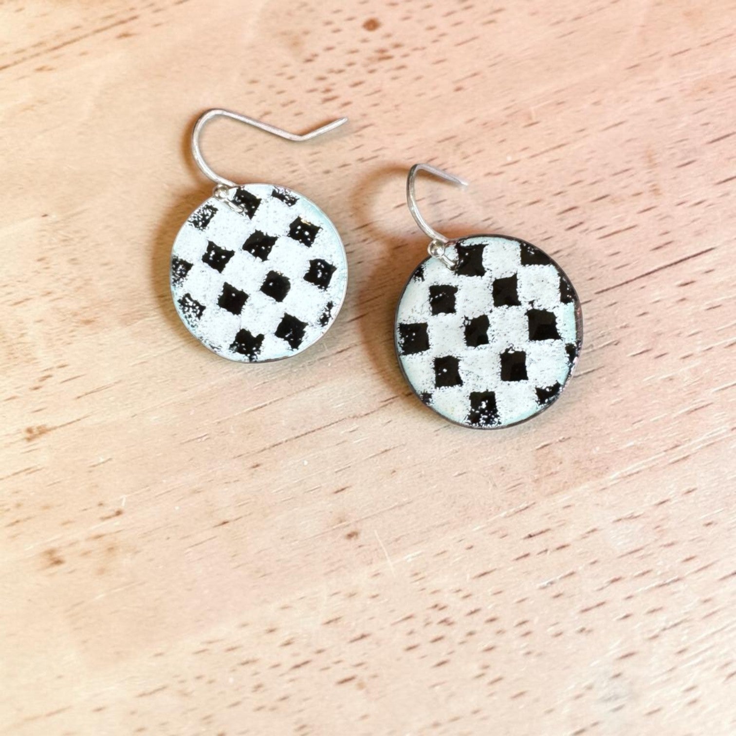 Bedrock Rose handmade round copper dangle earrings with a textured black and white kiln-fired enamel checkerboard.