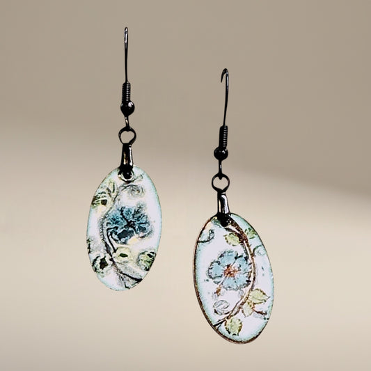 Bedrock Rose hand-painted oval dangle earrings with azure blue flowers and green leaves on white enamel.