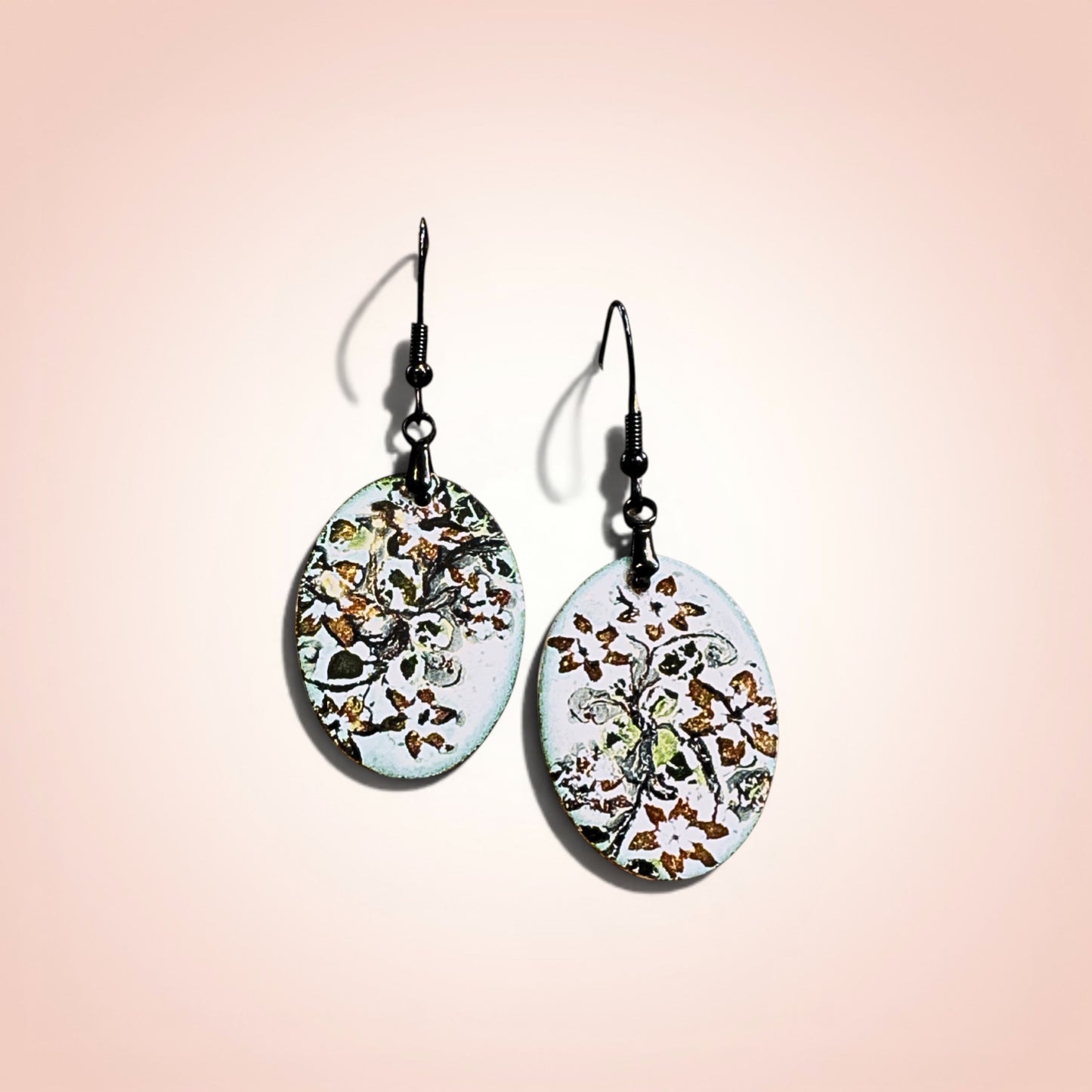 Bedrock Rose hand-enameled oval copper dangle earrings with black floral motif on white base.