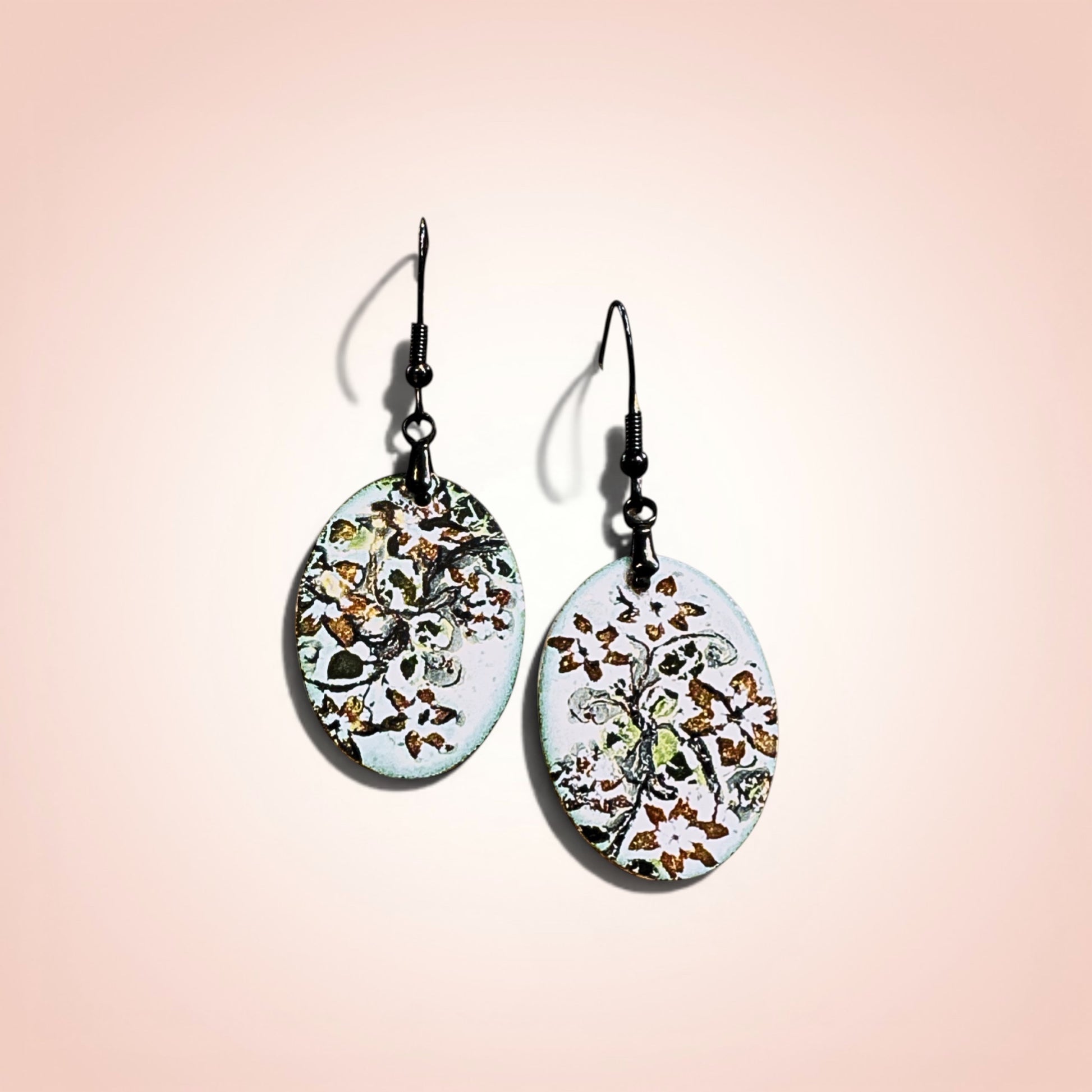 Bedrock Rose hand-enameled oval copper dangle earrings with black floral motif on white base.