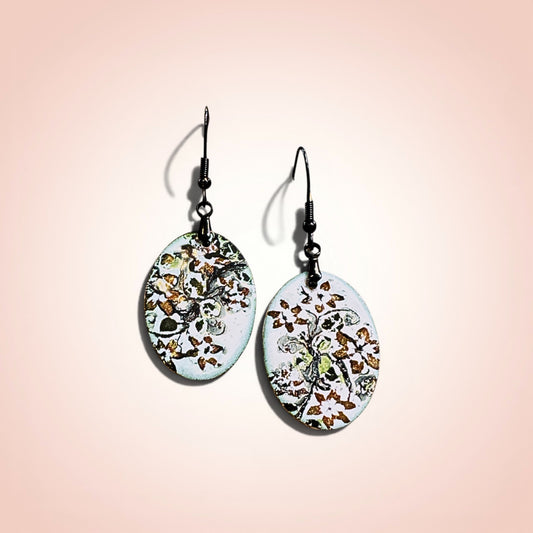 Bedrock Rose hand-enameled oval copper dangle earrings with black floral motif on white base.