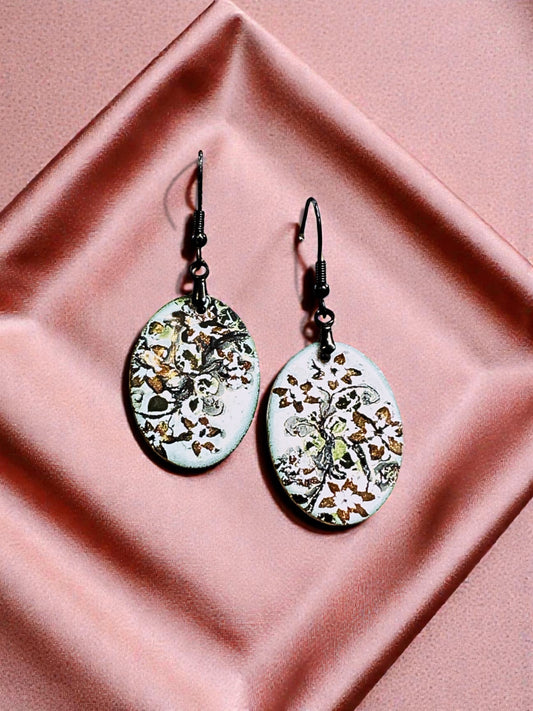 Bedrock Rose hand-enameled oval copper dangle earrings with white base and black floral motif.