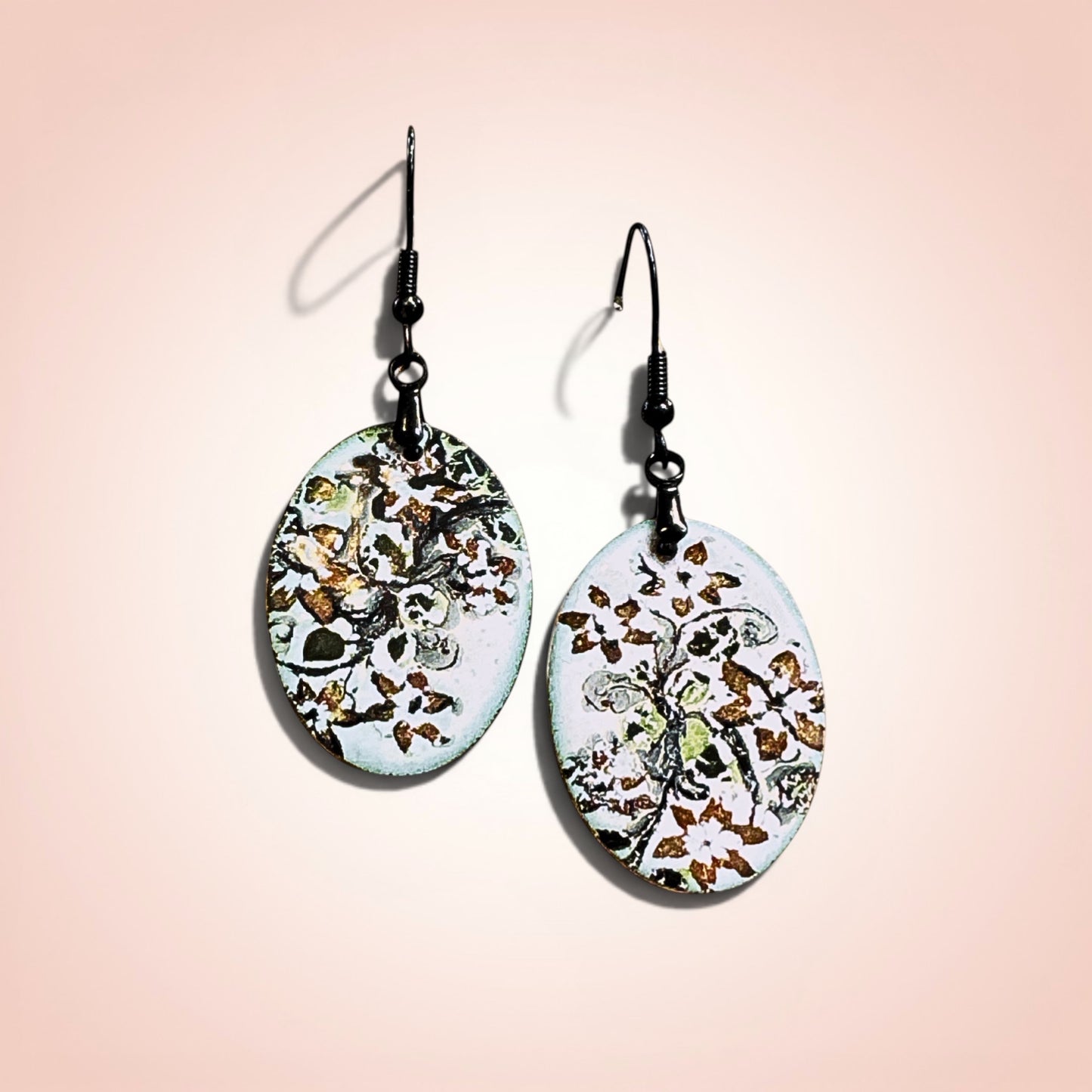 Bedrock Rose hand-enameled oval dangle earrings with white base and black floral motif. Copper earrings with glass-like finish.