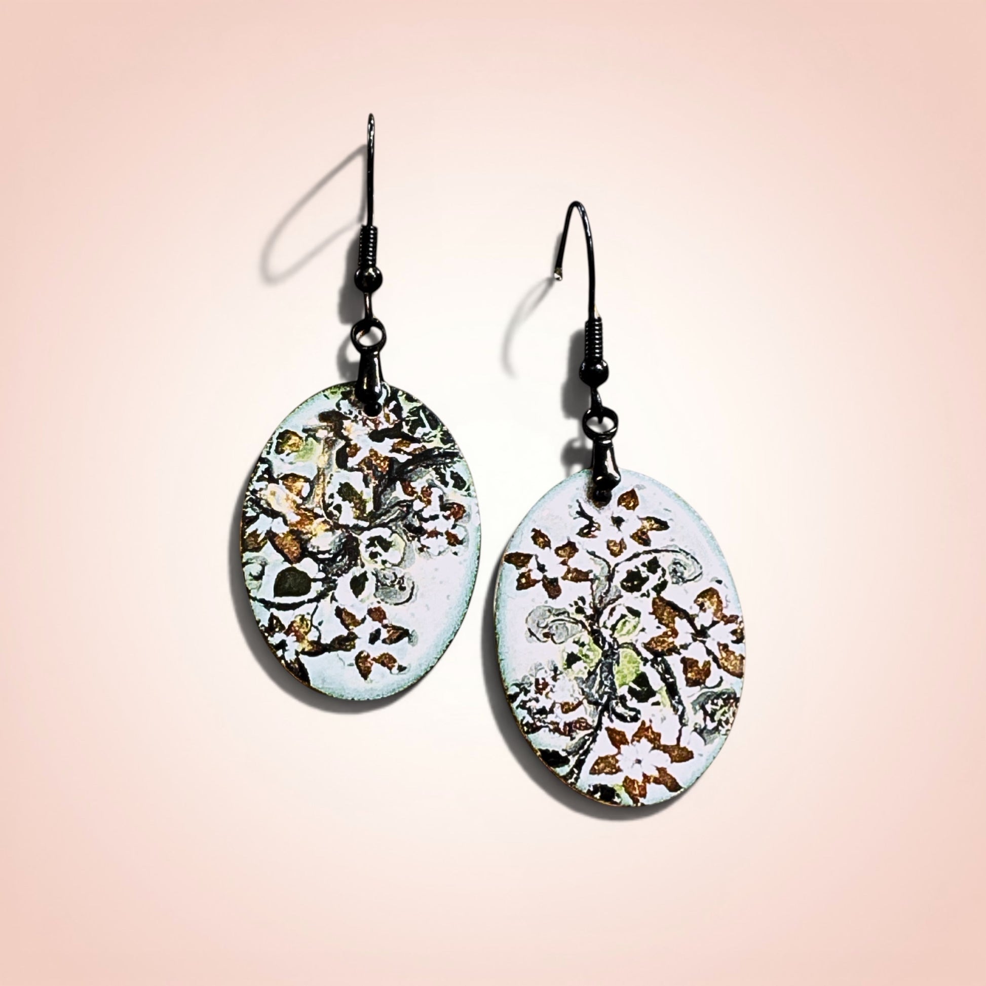 Bedrock Rose hand-enameled oval dangle earrings with white base and black floral motif. Copper earrings with glass-like finish.