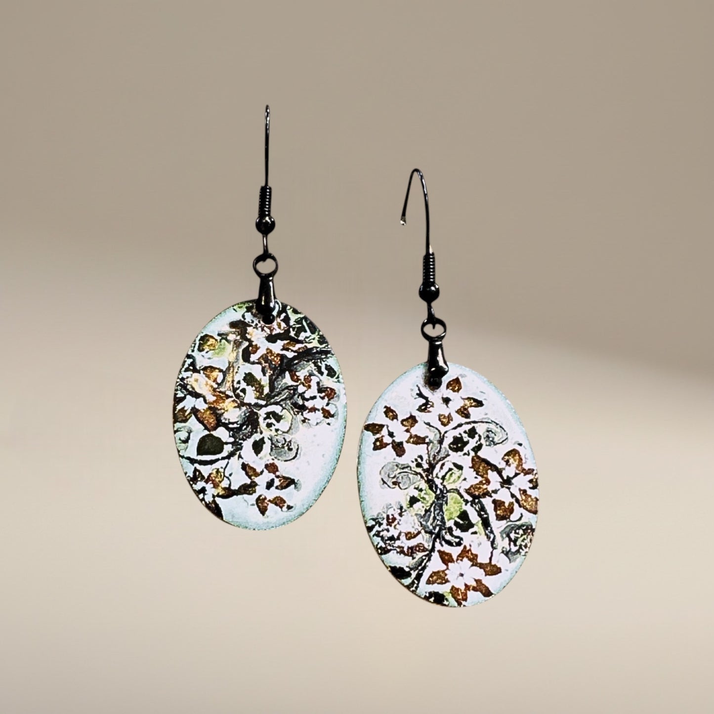 Bedrock Rose hand-enameled oval dangle earrings with white base and black floral motif. Copper earrings with glass-like finish.